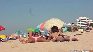 Девушки в бикини загорают на пляже, пока за ними подглядывает вуайеристка