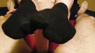 Голая сучка с пирсингом в пупке наяривает хер ножками в черных носках